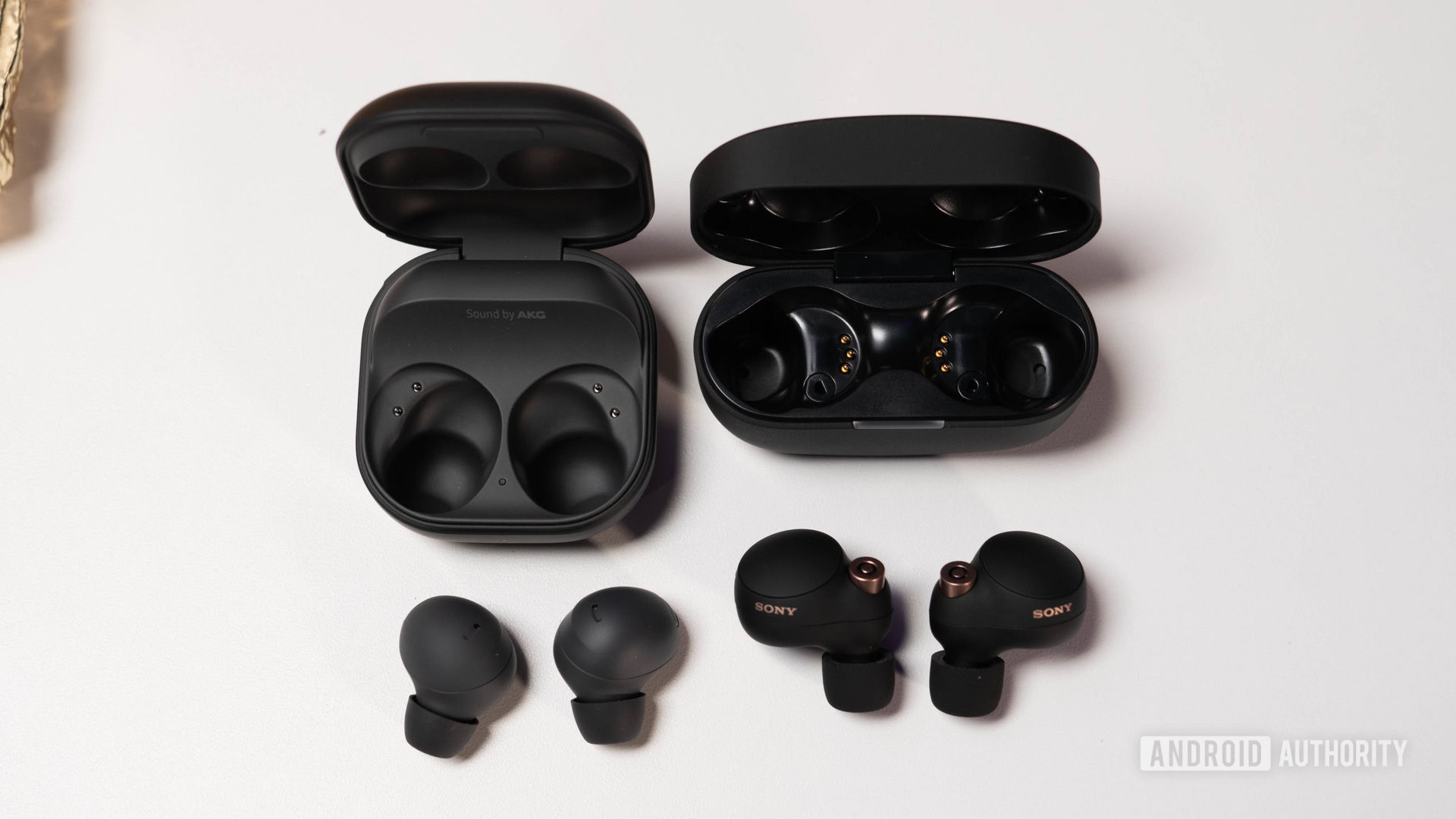 Samsung Galaxy Buds 2 Pro vs Sony WH 1000XM4 laying on table next to charging case