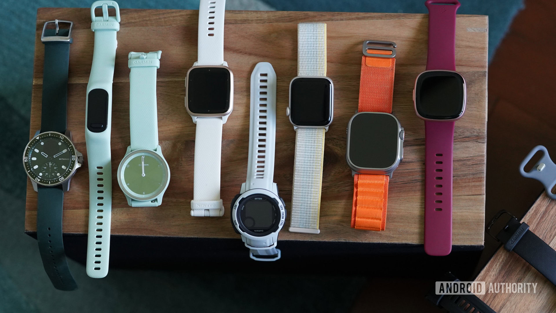 Wearables from various brands rest on a wooden box.