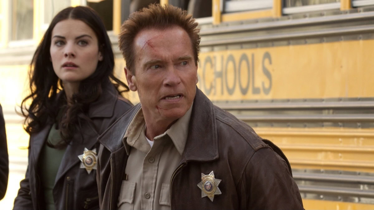 A sheriff and his deputy stand in front of a school bus in The Last Stand