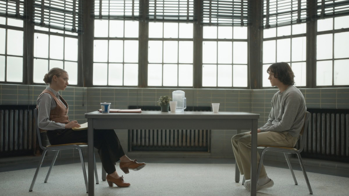 A man and woman sit across from each other at a table in The Crowded Room