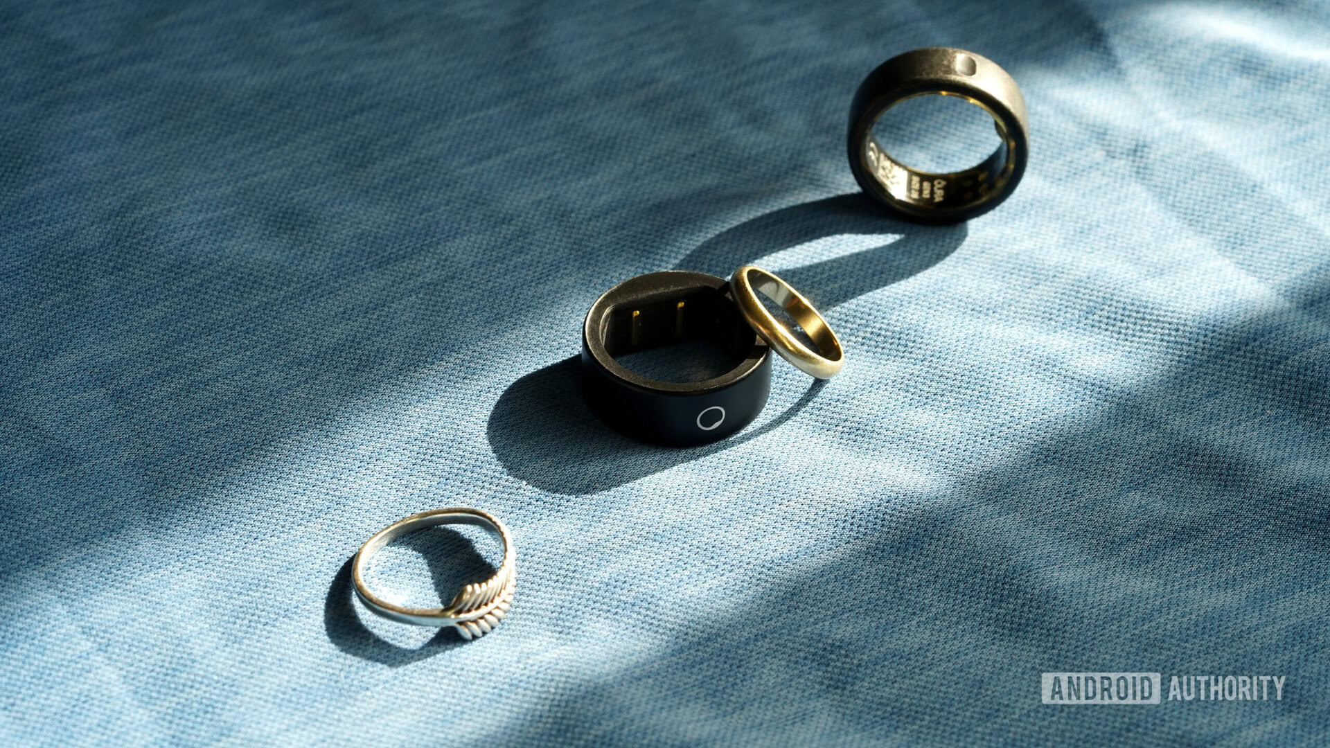 Une bague circulaire mince repose parmi les bijoux d'un utilisateur et une bague intelligente alternative.