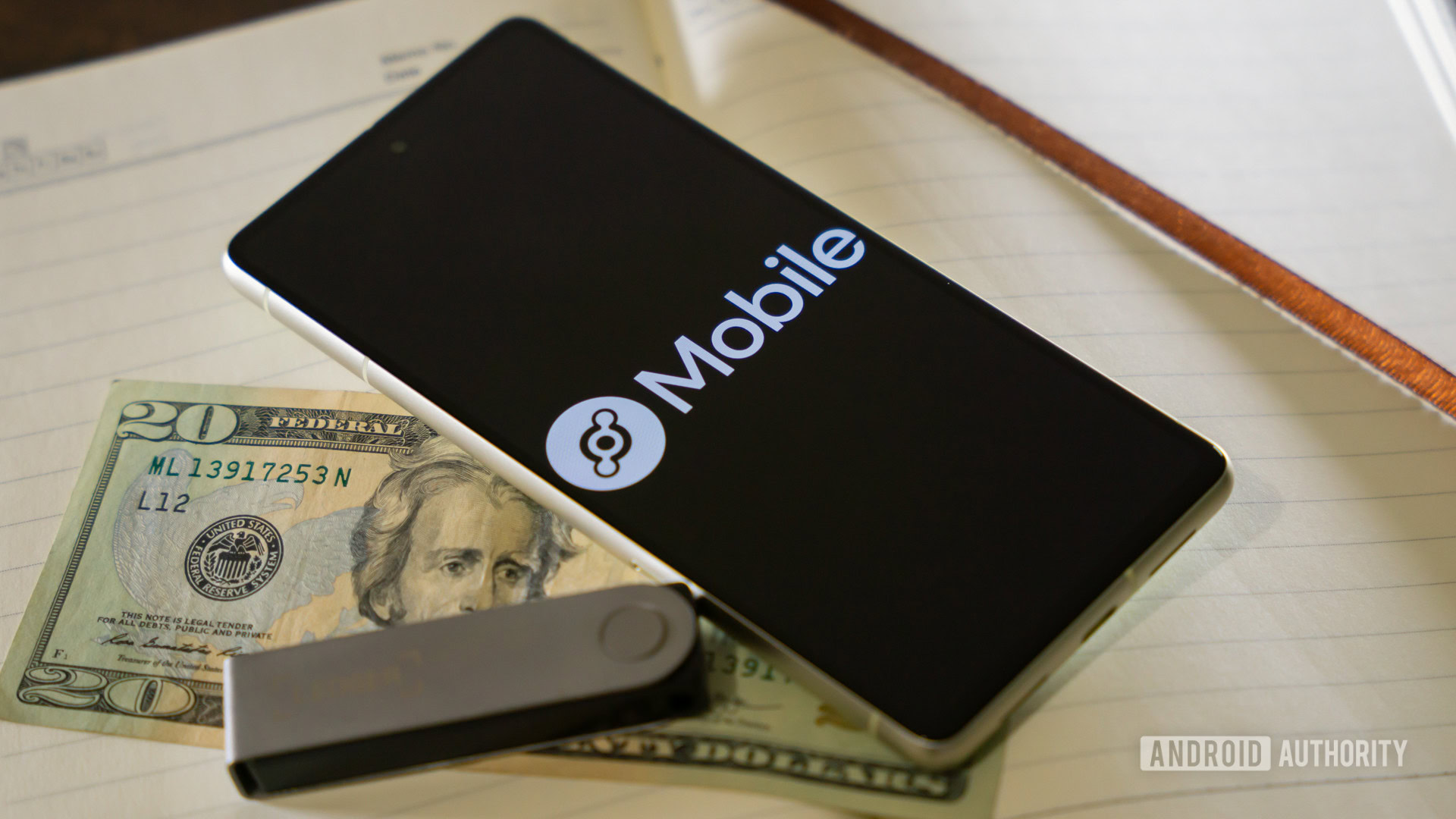 Helium Mobile logo on smartphone, next to money and crypto hardware wallet (2)