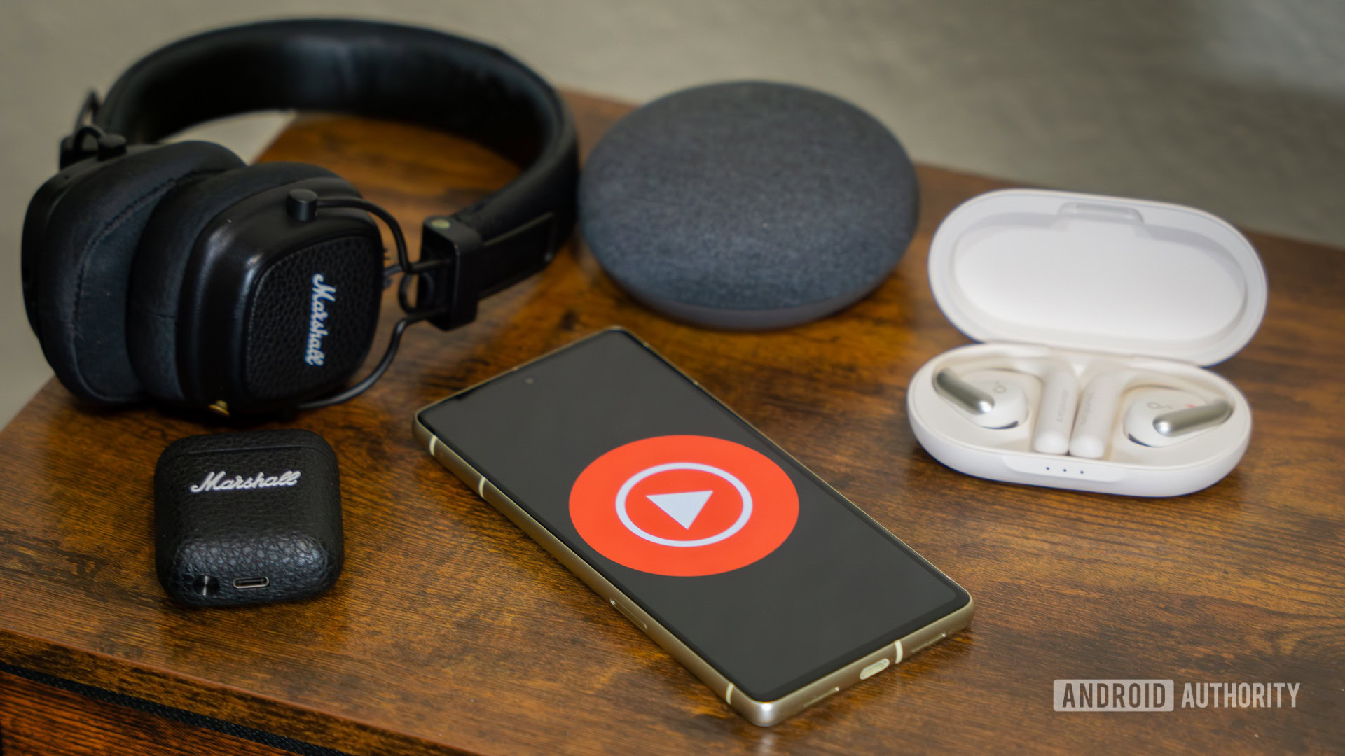 YouTube Music logo on smartphone, next to headphones and Nest Mini (1)