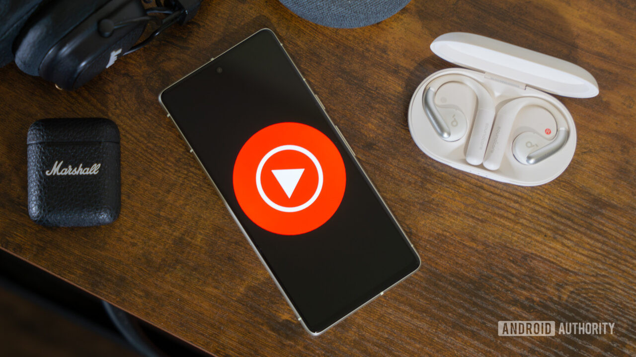 YouTube Music logo on smartphone, next to headphones and Nest Mini (2)