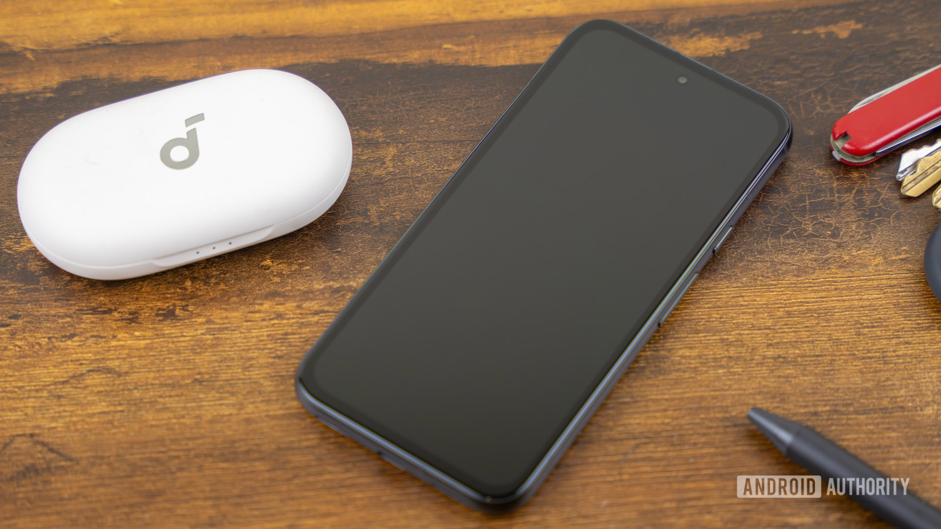 Google Pixel 8a laying on table with the screen off, next to other everyday items stock photo