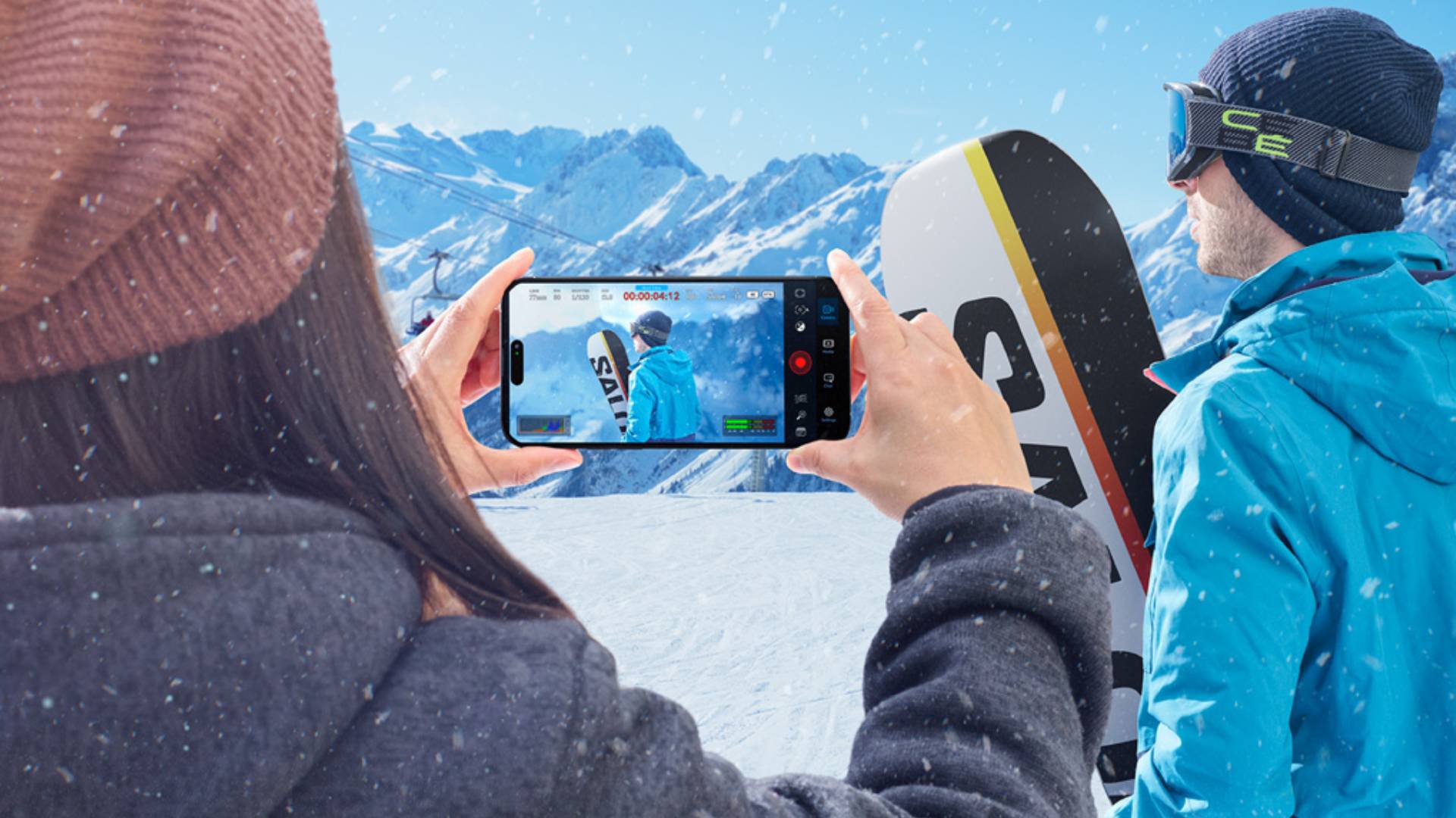 Person filming a snowboarderusing the Blackmagic Camera app on a smartphone with mountains in the background.