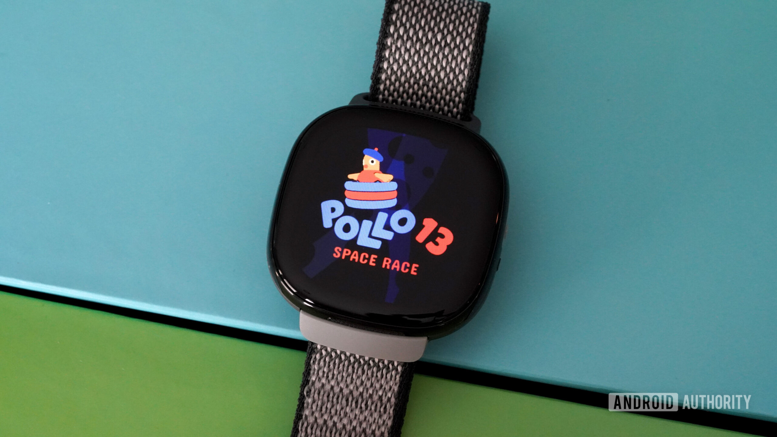 A Fitbit Ace LTE dispalys the Pollo 13 opening screen.