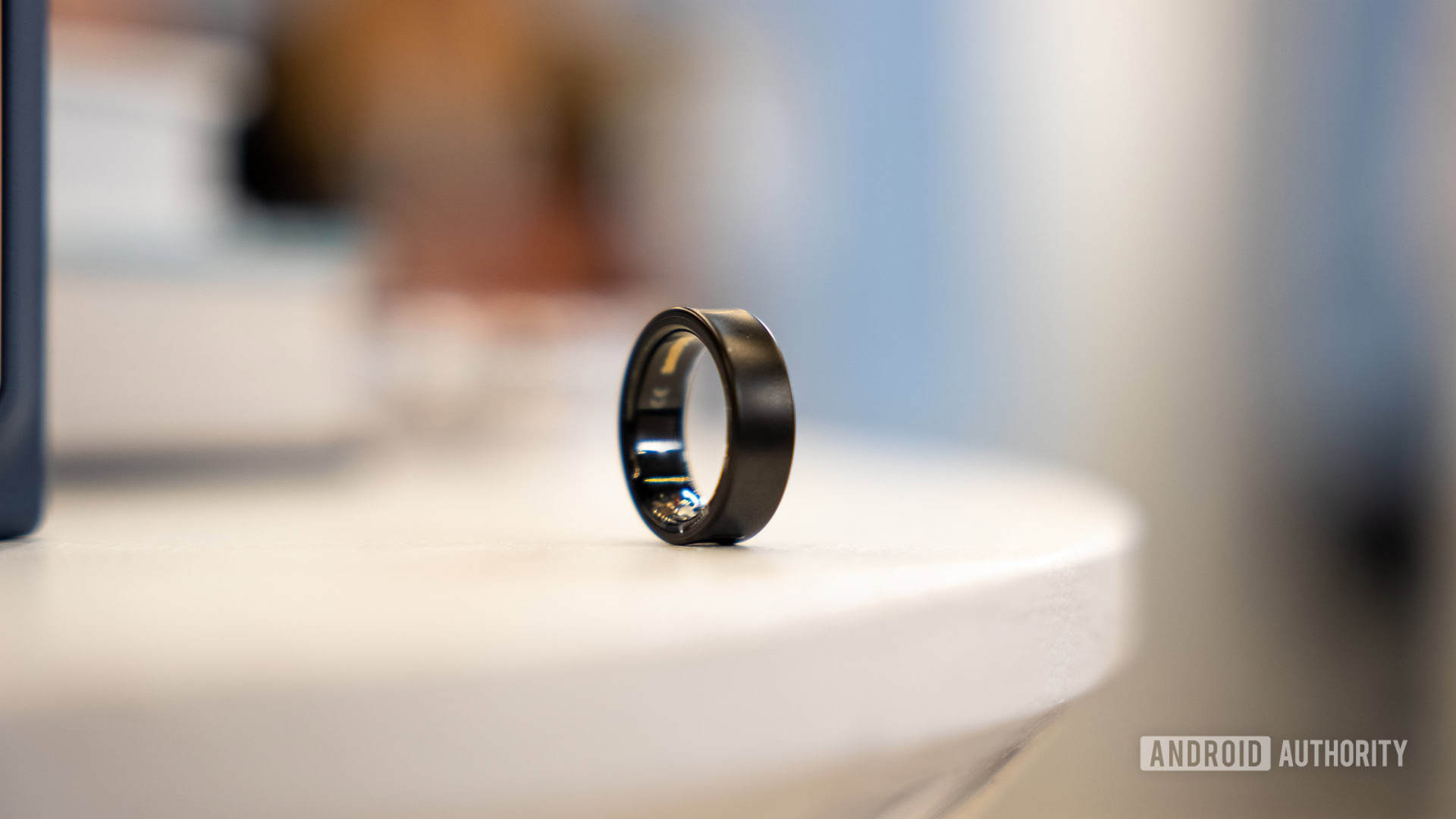 A Black Titanium Samsung Galaxy Ring rests on a white surface.