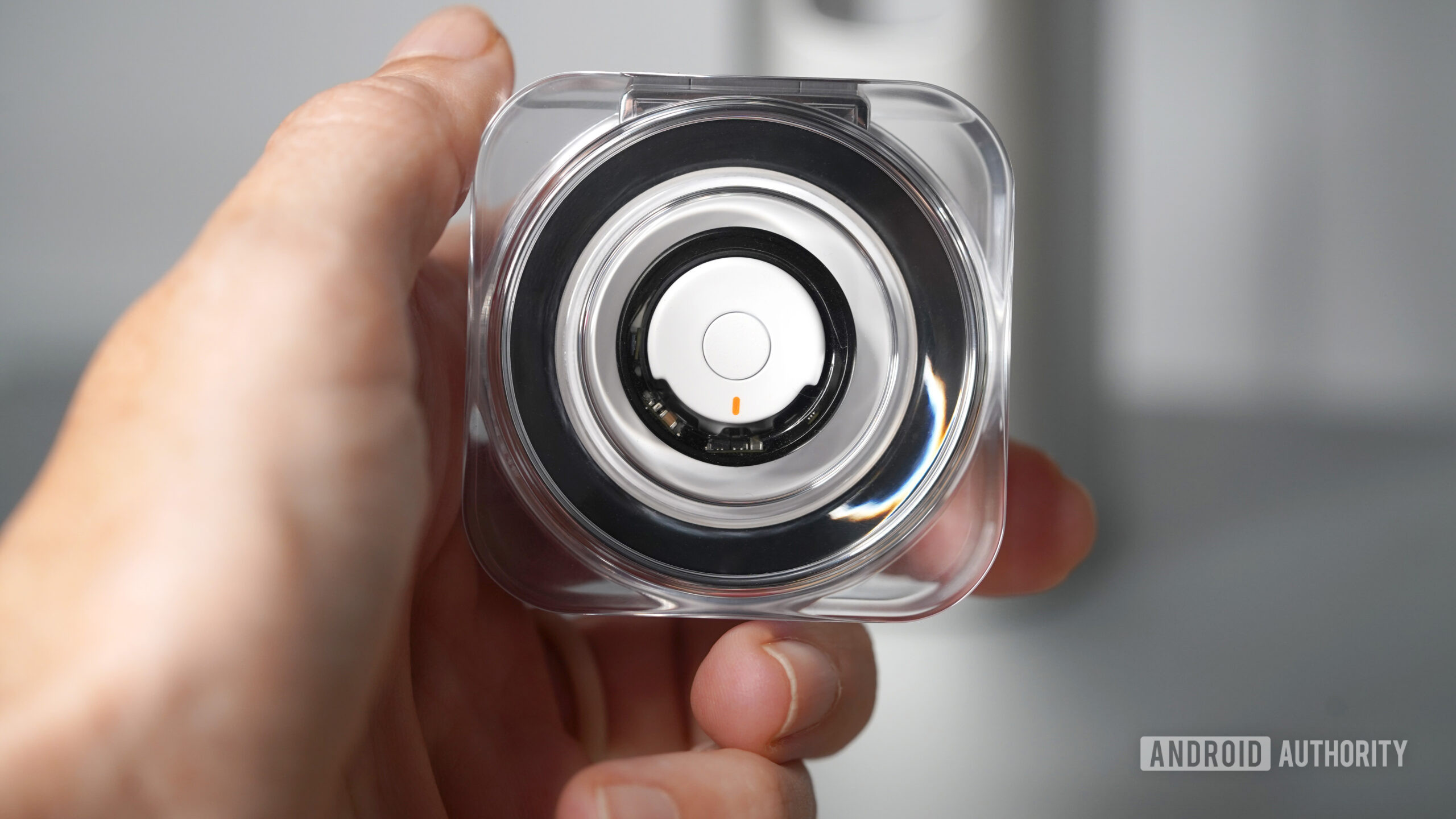 A user holds their transparent Samsung Galaxy Ring charging case with the ring charging inside. 