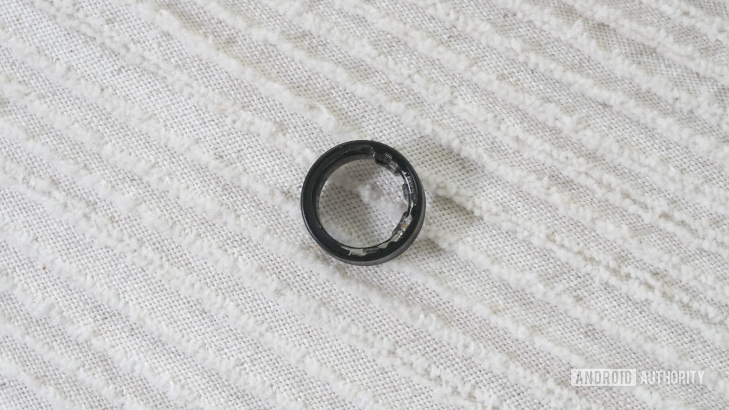 A Samsung Galaxy Ring rests on a pillow.