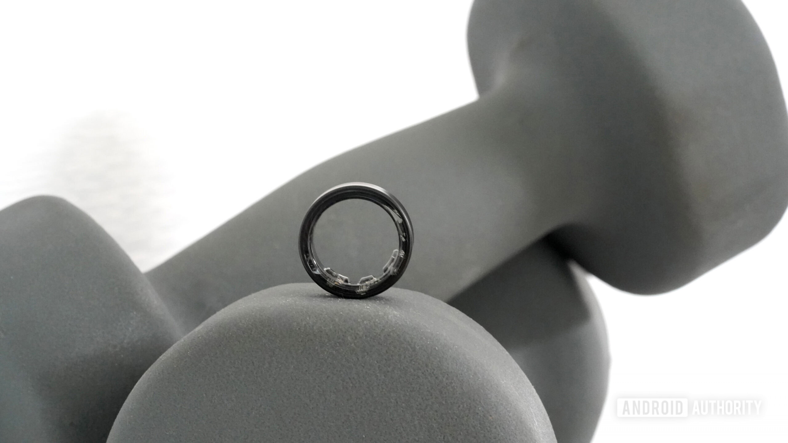 A Samsung Galaxy Ring rests on a set of hand weights.