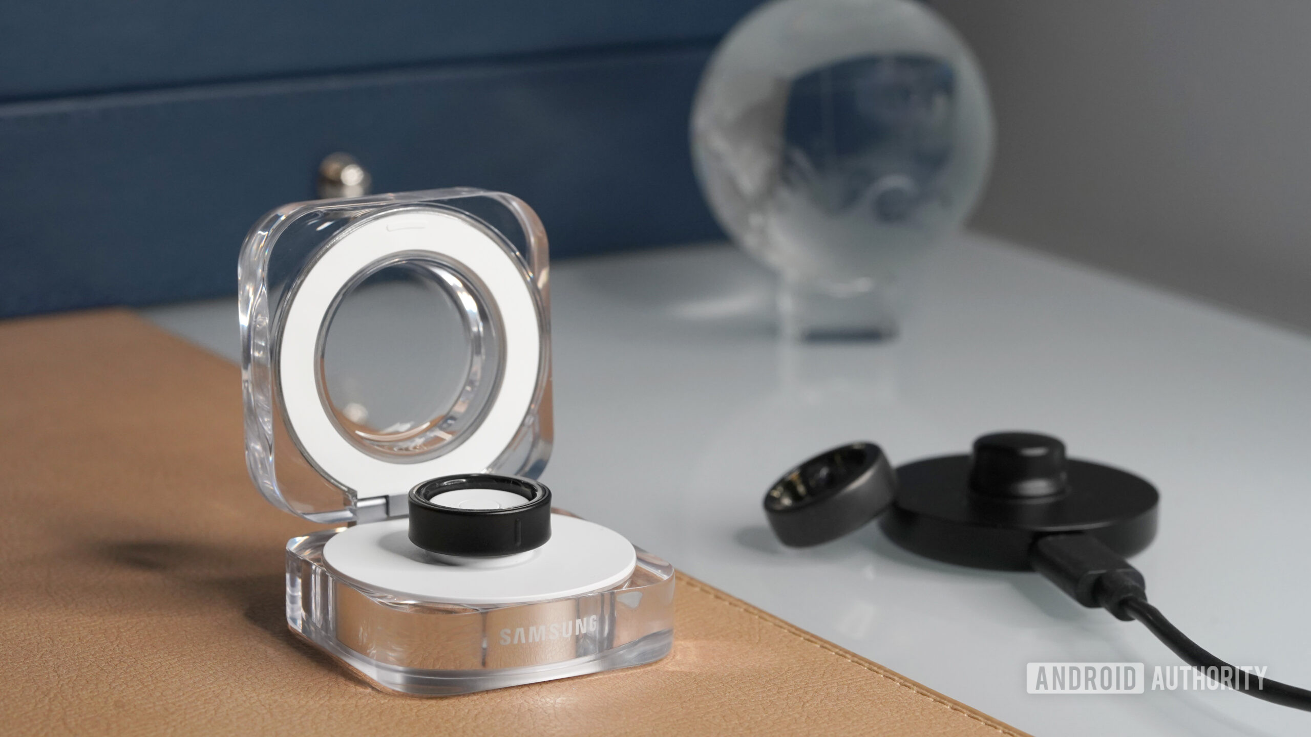 The Samsung Galaxy Ring charger features a clamshell design while Oura Ring 3 equips a cradle-style charger.