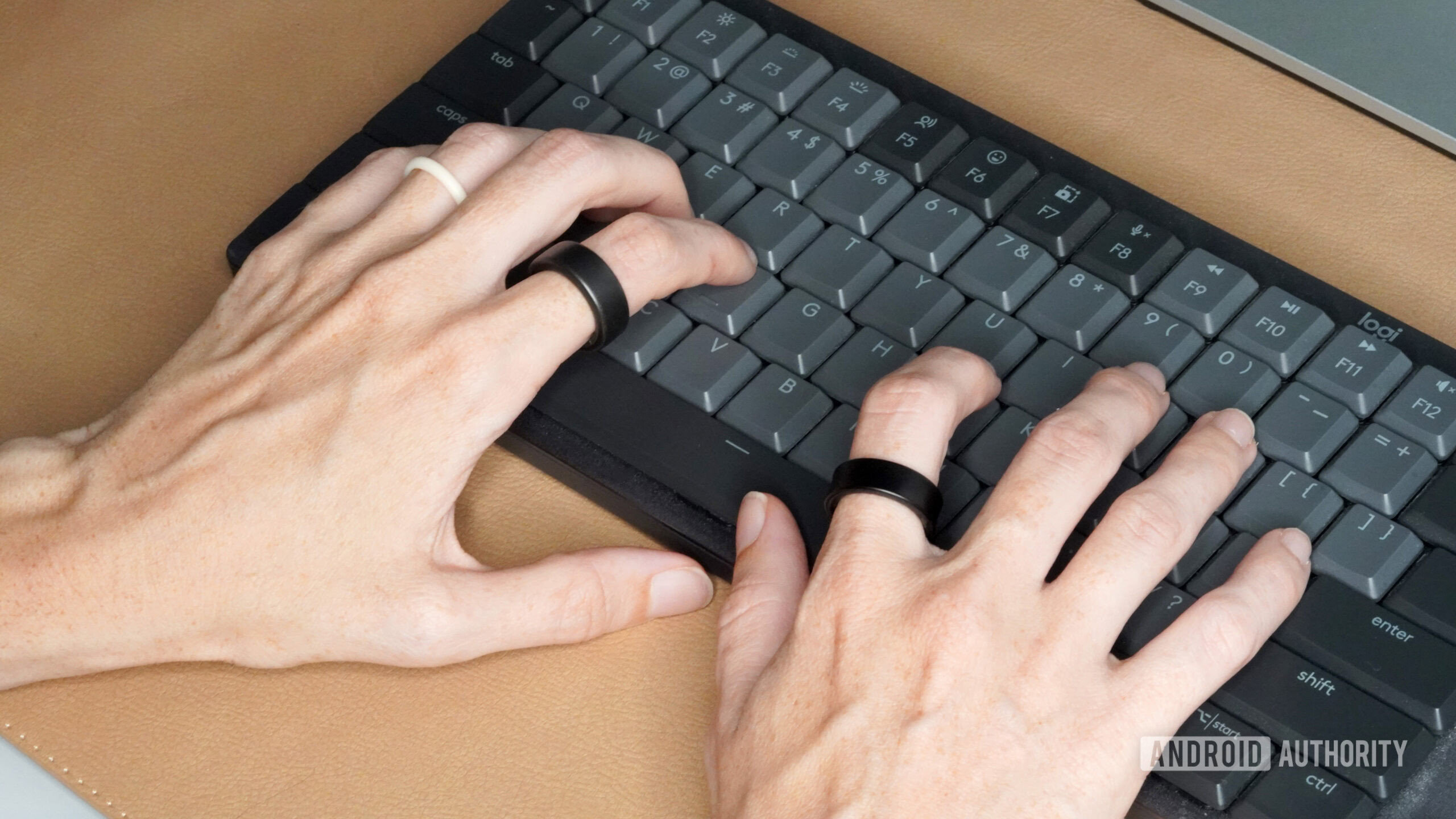 A woman wearing a Samsung Galaxy Ring and Oura Ring 3 types on a keyboard.