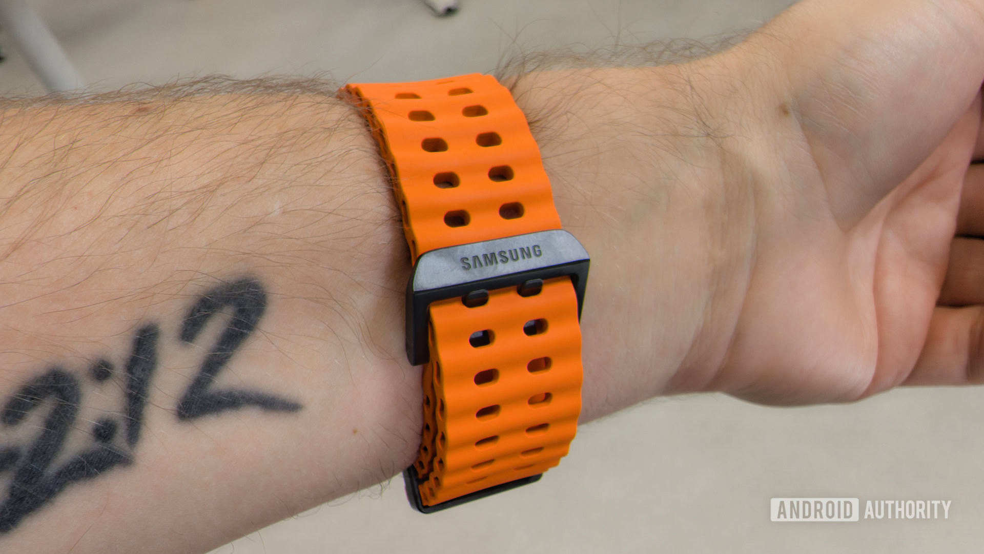 Samsung Galaxy Watch Ultra Orange Band Buckle as it Appears on Male Wrist