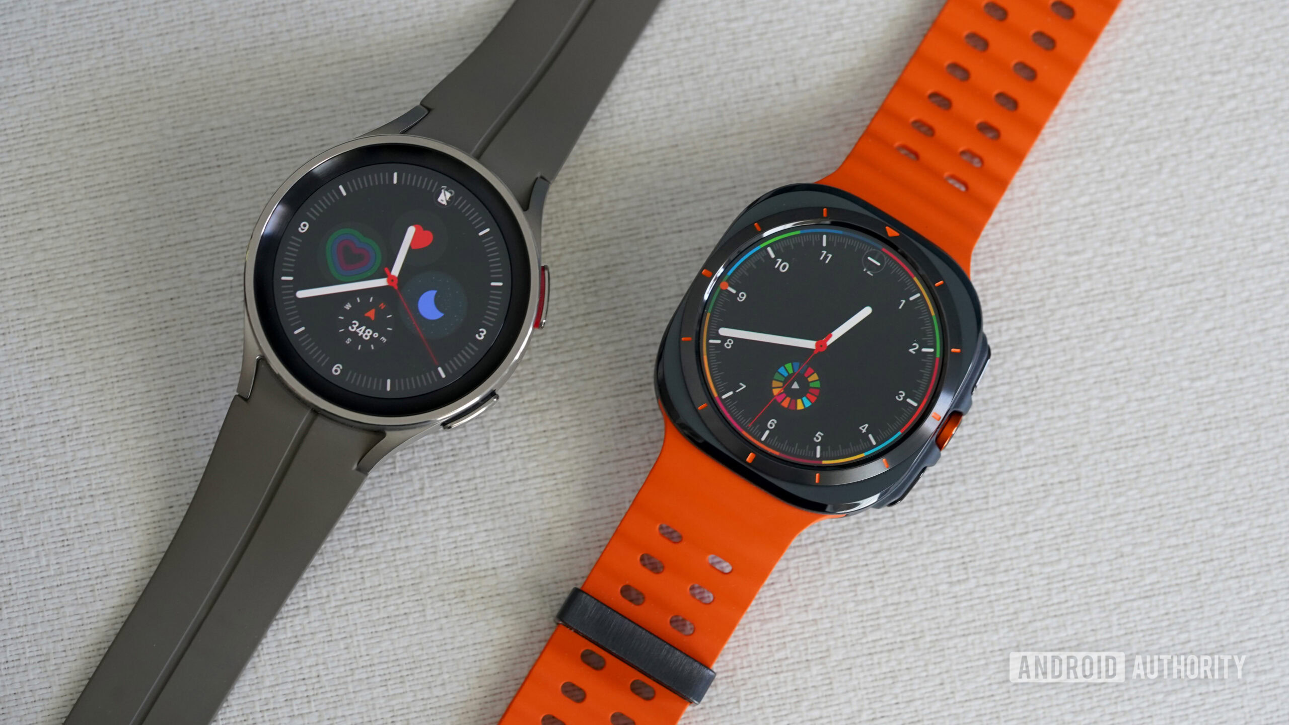 A Samsung Galaxy Watch Ultra rests alongside a Galaxy Watch 5 Pro, each display a watch face.