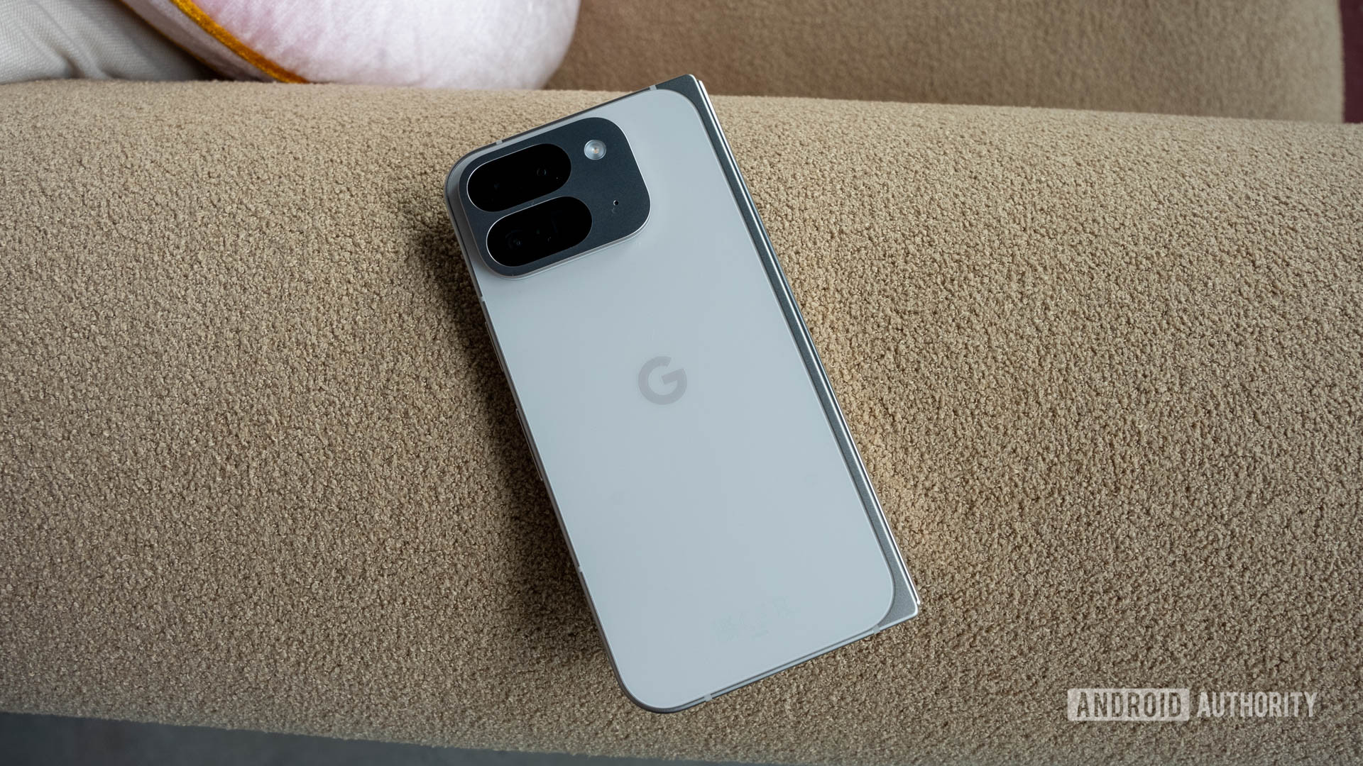 Google Pixel 9 Pro Fold in Porcelain color resting on arm of a couch