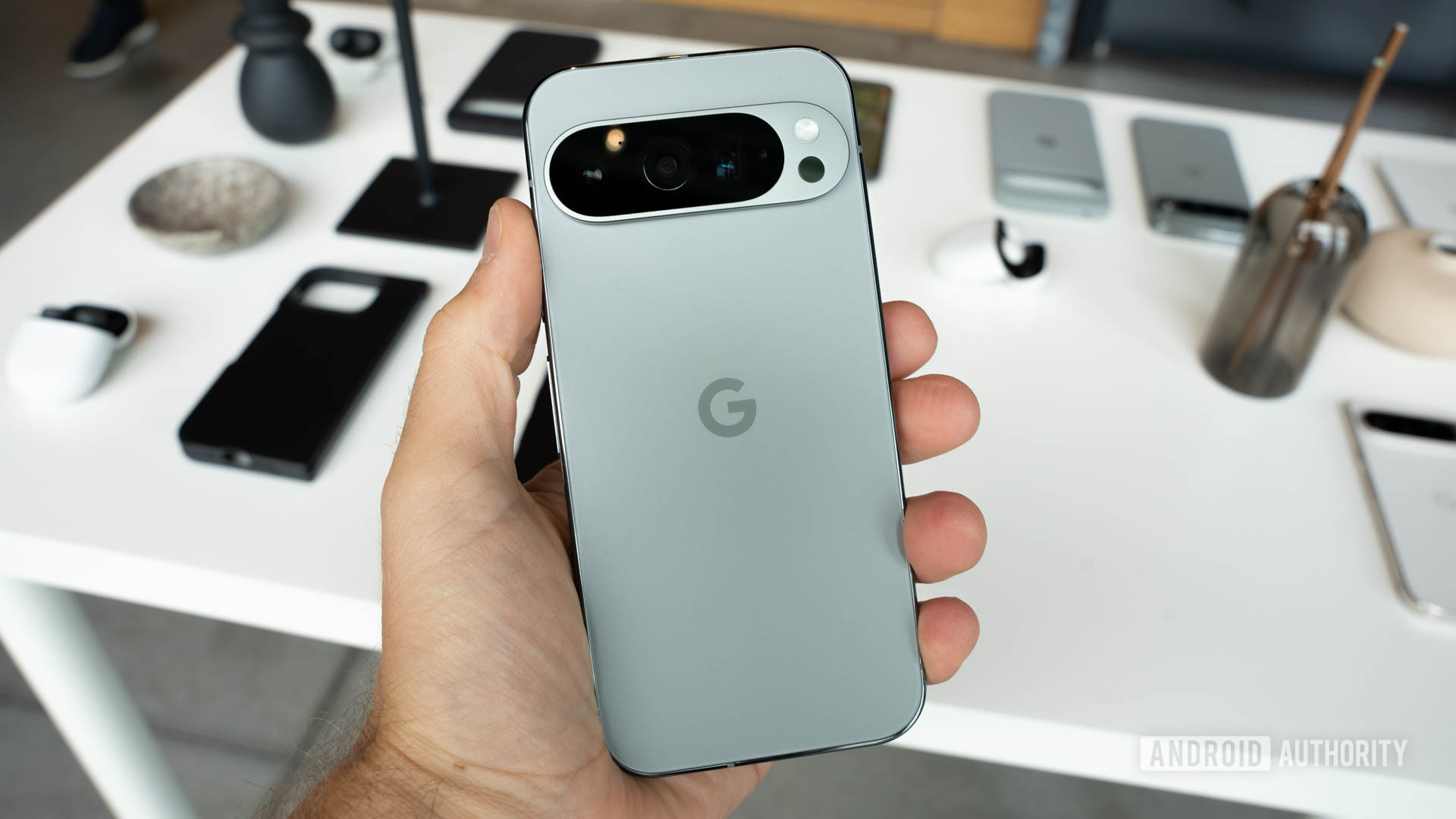 Google Pixel 9 Pro in Hazel color is held in a person's left hand with the display facing backwards