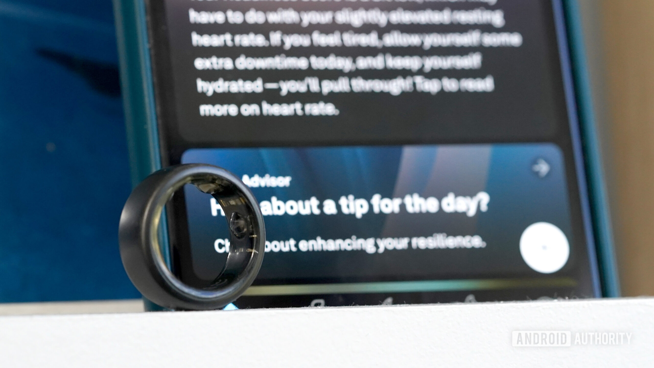 An Oura Ring 3 rests in front of a screen display the Oura Advisor prompt.