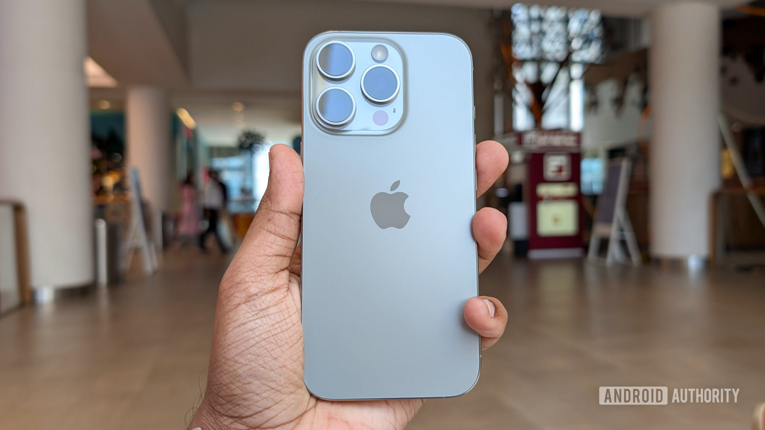 Apple iPhone 16 Pro in Natural Titanium color held out in hand