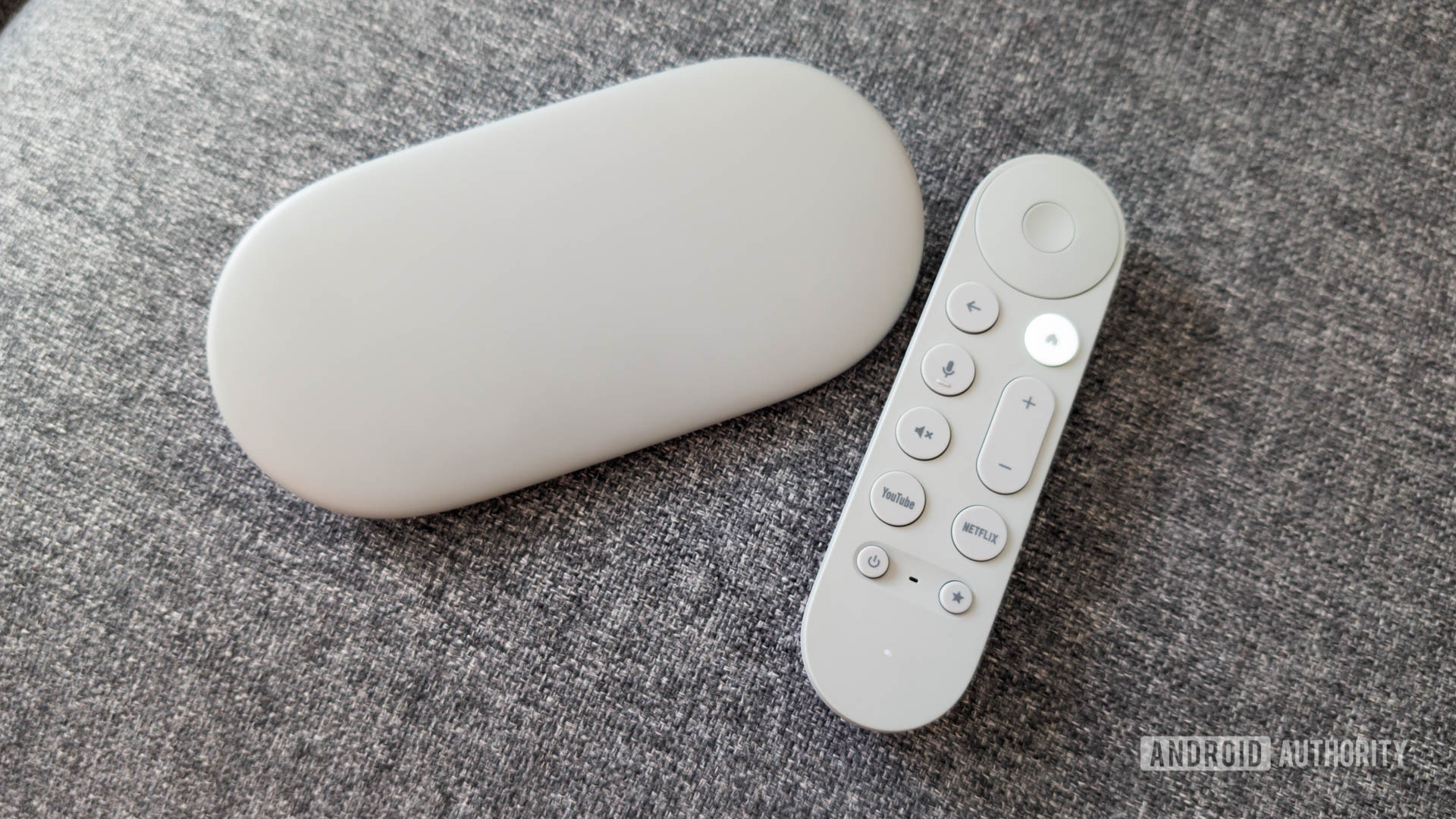 Google TV Streamer dengan remote di sofa