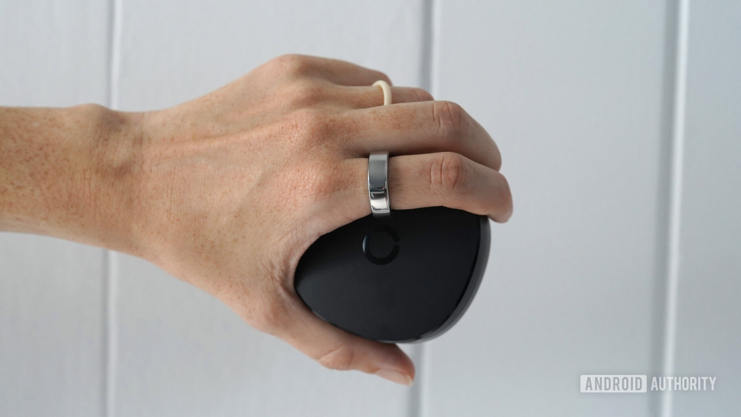 A smart ring user wears a RingConn Smart Ring Gen 2 while holding the device's charger.