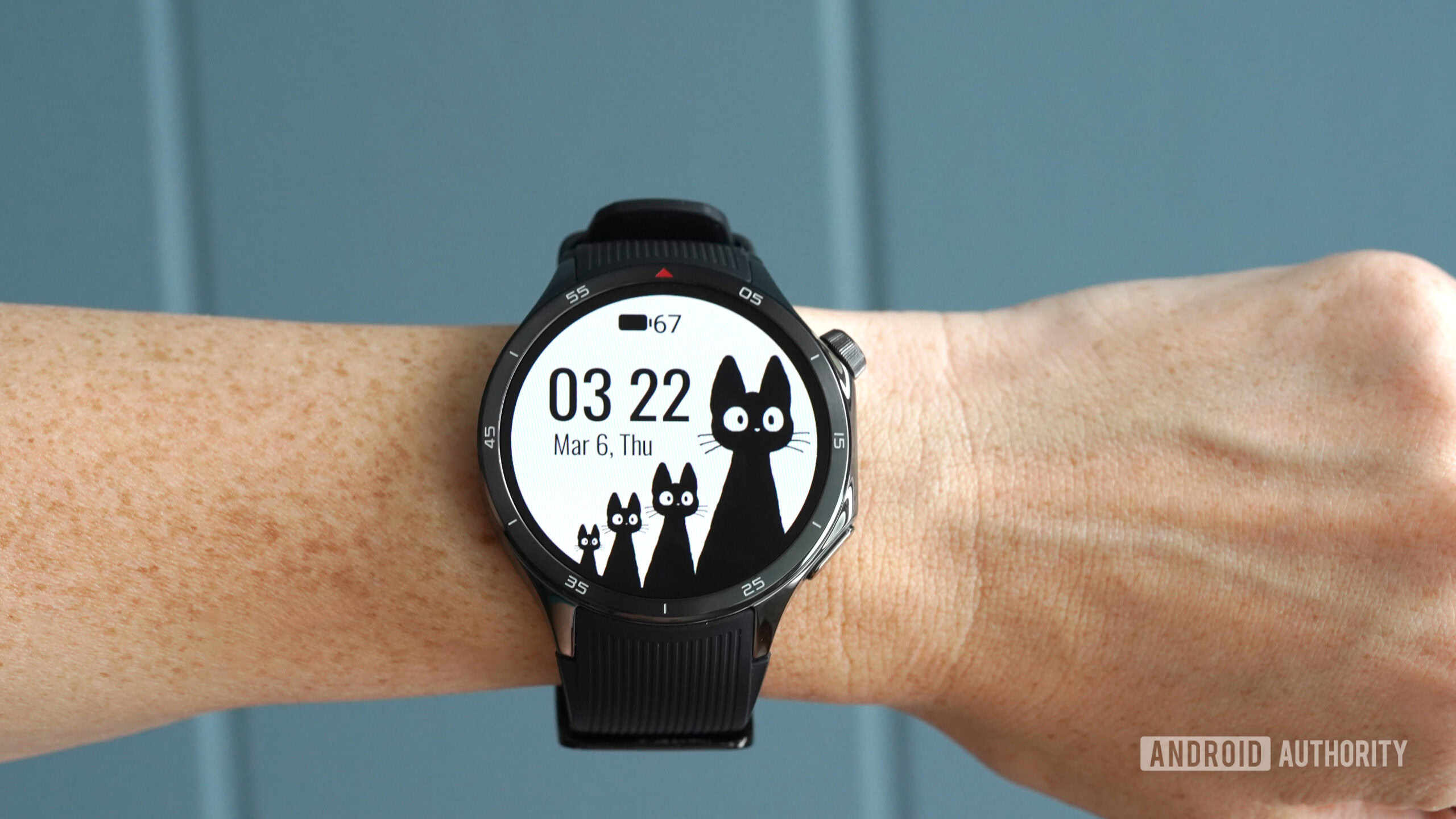 A OnePlus Watch 3 displays the Black Cats WearOS watch face.